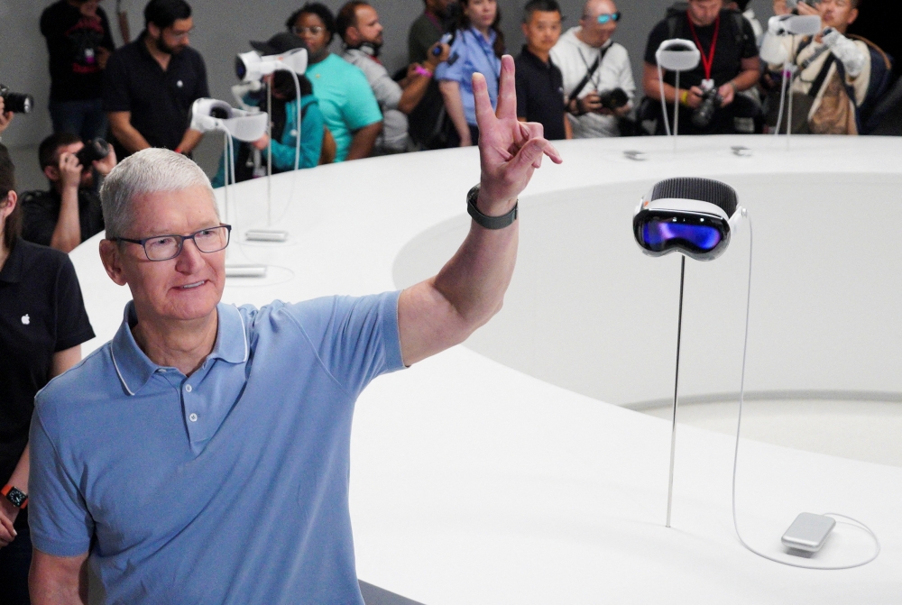 Apple CEO Tim Cook gestures next to Apple's Vision Pro headsets at Apple's annual Worldwide Developers Conference at the company's headquarters in Cupertino, California June 5, 2023. — Reuters pic